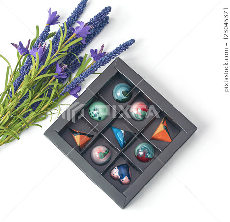 Tempered chocolate candies with glossy painted body in a box with blur elements. View from above 123045371