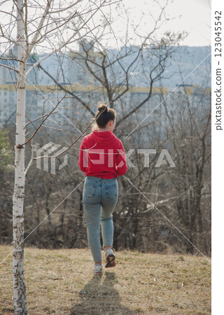 Woman in red hoodie walking in winter park scene Woman in red hoodie walking in winter park scene 123045542