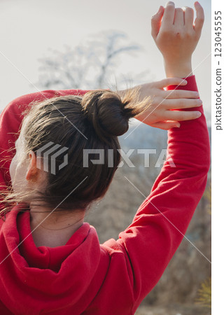 Relaxing outdoor stretch in bright red hoodie with nature background Relaxing outdoor stretch in bright red hoodie with nature background 123045555