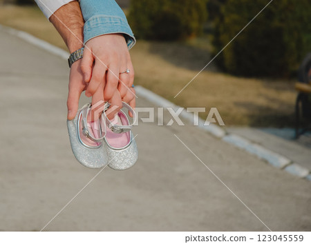 Expecting parents holding baby shoes outdoors symbolizing new journey and anticipation 123045559