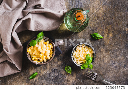 Pasta with grated cheese baked in a mug and basil leaves on the table top view 123045573