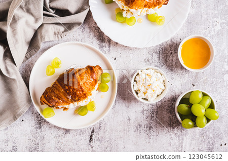 Delicious croissant with cottage cheese and grapes on a plate on the table top view 123045612