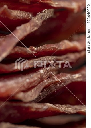 dried dried meat from meat tenderloin with spices and salt on black slate 123046020