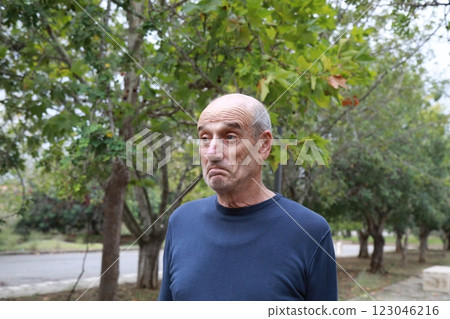 Elderly Man Makes Facial Expression Of We Hope Under A Tree In The Countryside 123046216