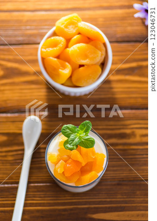 Light fruit yogurt with dried apricots on dark wooden table 123046731