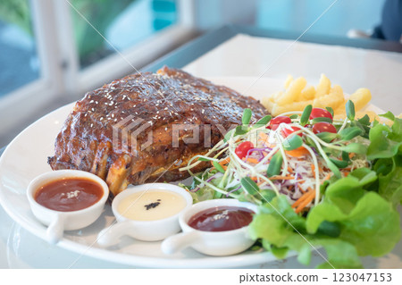 Pork rib steak served with vegetable salad and french fries Pork rib steak served with vegetable salad and french fries 123047153