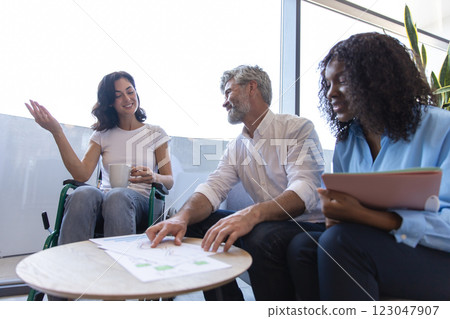 Diverse team in workplace including woman in wheelchair collaborating on business strategy Diverse team in workplace including woman in wheelchair collaborating on business strategy 123047907