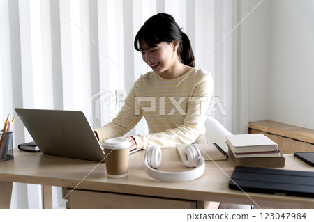 A young woman sitting at a table using a laptop 123047984