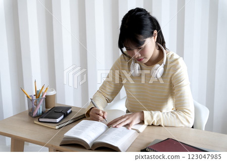 teenage woman is sitting on her home desk reading a book teenage woman is sitting on her home desk reading a book 123047985