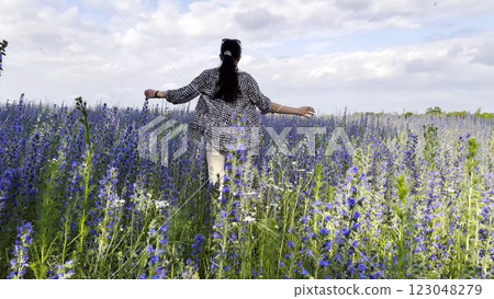 Young girl running through beautiful purple flowers field at summer day. Happy woman having fun while jogging among violet blossoms at meadow. Beautiful nature background. Freedom concept. Slow mo Young girl running through beautiful purple flowers field at summer day. Happy woman having fun while jogging among violet blossoms at meadow. Beautiful nature background. Freedom concept. Slow mo 123048279