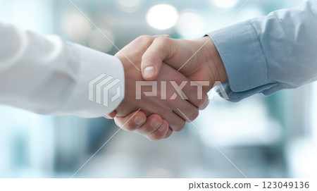 two professionals shaking hands in a bright modern office wearing formal shirts symbolizing agreement and trust with subtle copyspace concept of business, finance, marketing 123049136