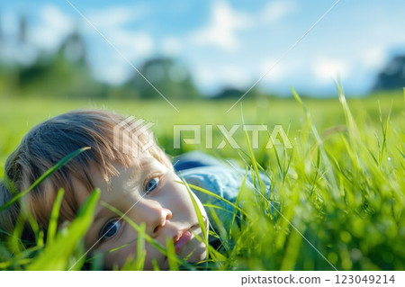 kid resting on soft green grass in sunlit field gazing calmly at the camera warm vibrant atmosphere copyspace concept of childcare, wellness, marketing kid resting on soft green grass in sunlit field gazing calmly at the camera warm vibrant atmosphere copyspace concept of childcare, wellness, marketing 123049214