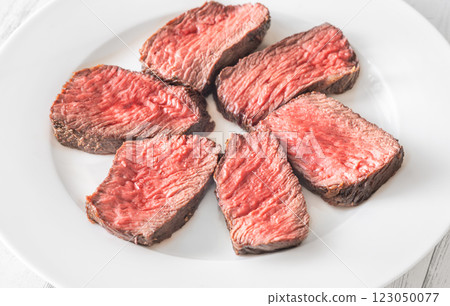 Perfectly sliced medium-rare fillet mignon steak served on a white plate 123050077