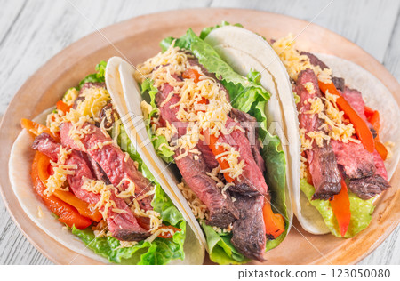 Three carne asada tacos filled with steak, grilled peppers, lettuce, and cheese 123050080