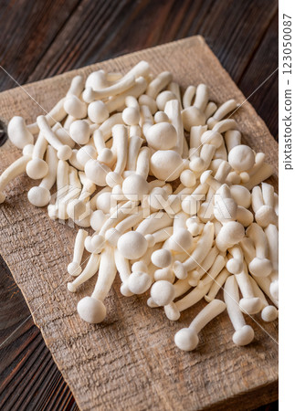 Fresh white beech mushrooms elegantly arranged on a rustic cutting board Fresh white beech mushrooms elegantly arranged on a rustic cutting board 123050087