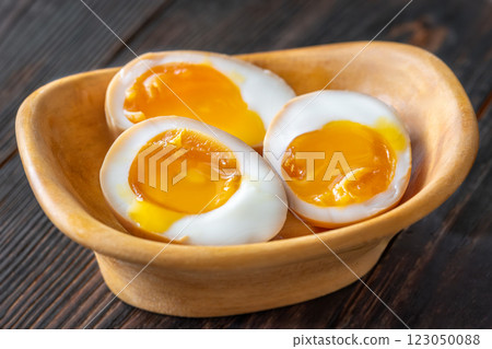 Halved ajitsuke tamago ramen eggs with golden yolks in wooden bowl Halved ajitsuke tamago ramen eggs with golden yolks in wooden bowl 123050088