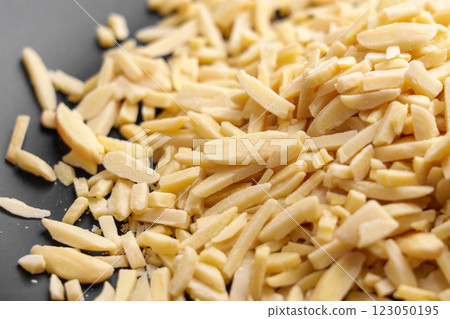 Slivered almonds scattered on a black plate. Baking and cooking ingredient, rich in nutrients. Organic raw nuts. Close-up Slivered almonds scattered on a black plate. Baking and cooking ingredient, rich in nutrients. Organic raw nuts. Close-up 123050195