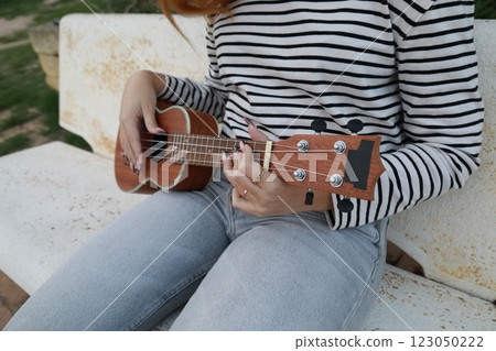 Artist Girl Plays Ukulele Musical Instrument Outside In Park Artist Girl Plays Ukulele Musical Instrument Outside In Park 123050222