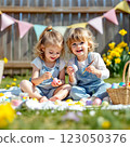 Children Participate in an Outdoor Egg Decorating Activity Surrounded by Flowers and Festive Decorations on a Sunny Day 123050376