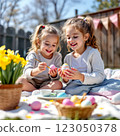 Two Children Enjoy Painting Easter Eggs in a Sunny Garden Surrounded by Colorful Flowers and Festive Decorations 123050378