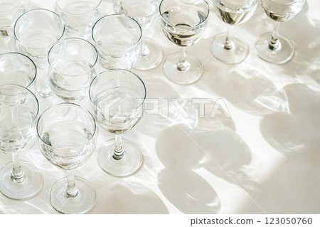 Empty crystal wine glasses casting shadows on white tablecloth Empty crystal wine glasses casting shadows on white tablecloth 123050760