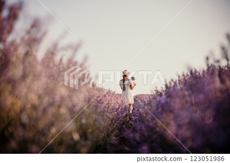 Lavender field girl. Back view happy girl in white dress with a scythe runs through a lilac field of lavender. Aromatherapy travel 123051986