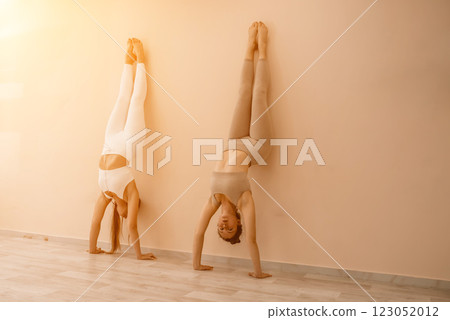 Two beautiful women cook doing yoga, sports together in the gym. Dressed in pink suits. The concept of grace and beauty of the body. Two beautiful women cook doing yoga, sports together in the gym. Dressed in pink suits. The concept of grace and beauty of the body. 123052012