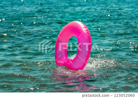 Inflatable Ring Water Ocean Summer: A pink inflatable ring floats in the turquoise water on a sunny summer day. 123052060