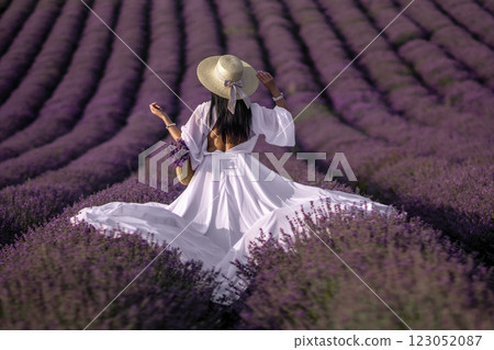 Lavender Provence Woman Dress: A woman in a white dress strolls through a vast French lavender field, enjoying the summer bloom. Lavender Provence Woman Dress: A woman in a white dress strolls through a vast French lavender field, enjoying the summer bloom. 123052087