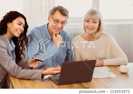 Preparing For A Trip. Mexican travel agent working with elderly clients and offering them tours at office using laptop Preparing For A Trip. Mexican travel agent working with elderly clients and offering them tours at office using laptop 123053072
