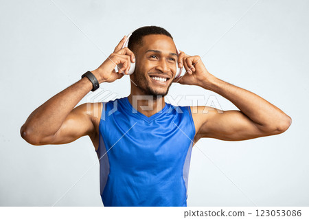 Active Lifestyle. Portrait of black man with perfect muscular body listening to music during training, yellow wall Active Lifestyle. Portrait of black man with perfect muscular body listening to music during training, yellow wall 123053086