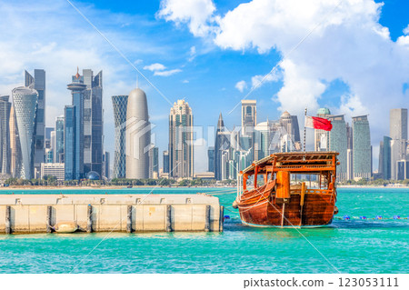 Traditional arab dhow fishermen boat with qatari flag at the sea bay with Doha futuristic business downtown center skyline, Qatar 123053111
