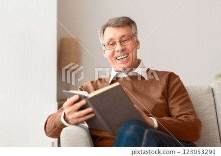 Happy Retirement. Senior Man Reading Book Relaxing Sitting On Sofa At Home. Selective Focus Happy Retirement. Senior Man Reading Book Relaxing Sitting On Sofa At Home. Selective Focus 123053291