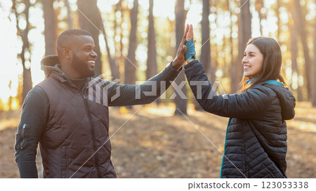 African guy giving girl high five to pretty girl over tent, camping in autumn forest, copy space African guy giving girl high five to pretty girl over tent, camping in autumn forest, copy space 123053338