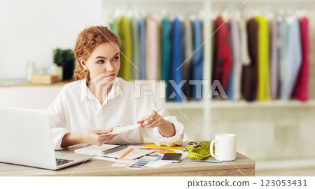 Portrait of female fashion stylist holding color samples choosing design for new dress, looking away, copy space 123053431
