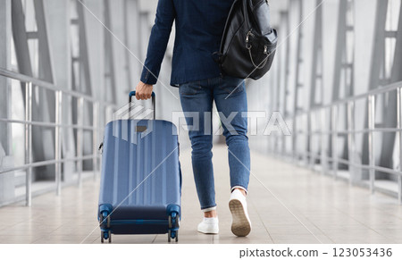 Unrecognizable Man With Bag And Suitcase Walking In Airport Terminal, Rear View Of Young Male On His Way To Flight Boarding Gate, Ready For Business Travel Or Vacation Journey, Cropped, Copy Space 123053436