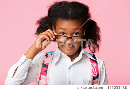 Home Education. Little School Girl Looking At Camera Under Eyeglasses Posing Over Yellow Background. Studio Shot Home Education. Little School Girl Looking At Camera Under Eyeglasses Posing Over Yellow Background. Studio Shot 123053488