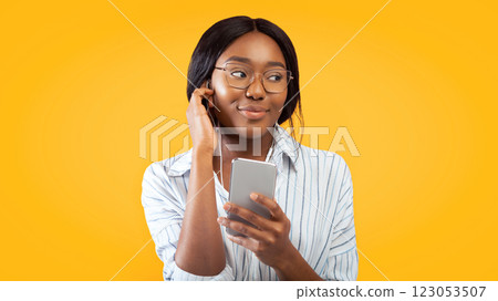 African American Girl Using Phone And Earphones Listening To Audio Book Standing On Pink Background. Studio Shot African American Girl Using Phone And Earphones Listening To Audio Book Standing On Pink Background. Studio Shot 123053507