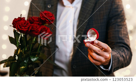 Valentine's Day Proposal. Romantic Man With Engagement Ring And Roses Flowers Asking Girlfriend To Marry Him Valentine's Day Proposal. Romantic Man With Engagement Ring And Roses Flowers Asking Girlfriend To Marry Him 123053523