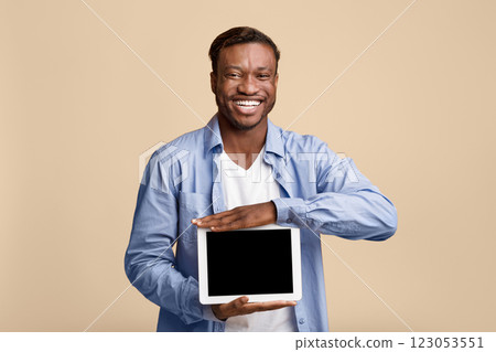 Great App. Smiling African American Man Showing Empty Tablet Screen On Yellow Background In Studio. Mockup Great App. Smiling African American Man Showing Empty Tablet Screen On Yellow Background In Studio. Mockup 123053551