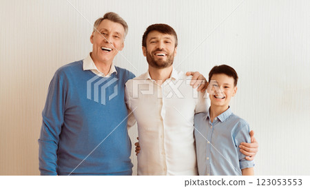 Cheerful Man, His Son And Elderly Father Embracing Standing Over White Wall Indoor. Male Generations Family Concept. Panorama Cheerful Man, His Son And Elderly Father Embracing Standing Over White Wall Indoor. Male Generations Family Concept. Panorama 123053553