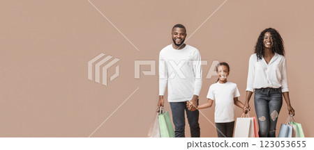 Shopping Weekend. Happy African American family of three walking with shopper bags in studio, yellow background with copy space 123053655