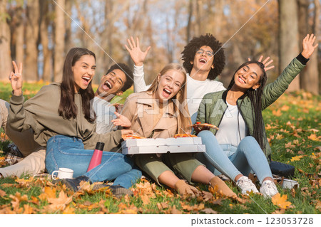 Emotional international friends enjoying sunny day, having picnic with pizza at park Emotional international friends enjoying sunny day, having picnic with pizza at park 123053728
