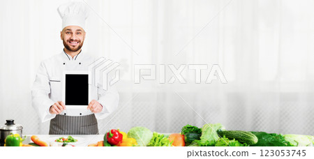 Cooking App. Chef Man Showing Digital Tablet With Empty Screen Advertising Menu Or Restaurant Application Standing In Kitchen Indoor. Mockup 123053745