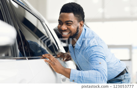 Happy Car Owner. African Guy Touching His New Vehicle Excited About Buying Automobile In Dealership Showroom. Selective Focus Happy Car Owner. African Guy Touching His New Vehicle Excited About Buying Automobile In Dealership Showroom. Selective Focus 123053777