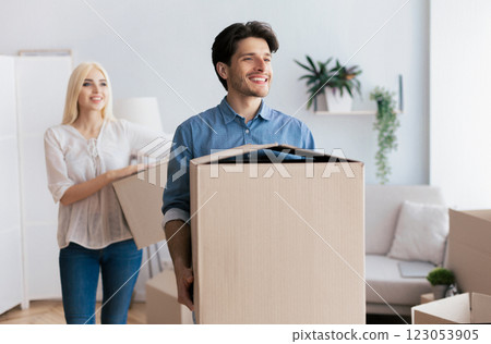 A man and woman carry boxes into a new home. The man is smiling as he looks towards the future. A man and woman carry boxes into a new home. The man is smiling as he looks towards the future. 123053905