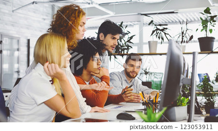 Young team analyzing new information, looking at computer monitor together, empty space 123053911