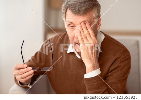 Glaucoma. Tired Elderly Man Massaging Eye Holding Eyeglasses Having Eyestrain And Ocular Tension Sitting On Couch At Home. Selective Focus Glaucoma. Tired Elderly Man Massaging Eye Holding Eyeglasses Having Eyestrain And Ocular Tension Sitting On Couch At Home. Selective Focus 123053923