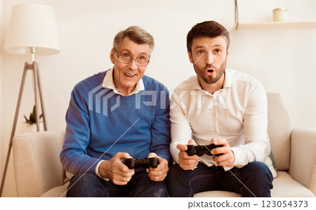 Mature Son And Elderly Father Playing Video Game Having Fun Together Sitting On Sofa Indoor. Different Generations Friendship 123054373