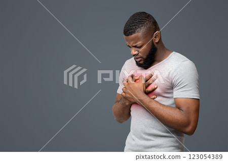 Sad young black man rubbing his chest over white background, free space, heart disease in young age Sad young black man rubbing his chest over white background, free space, heart disease in young age 123054389